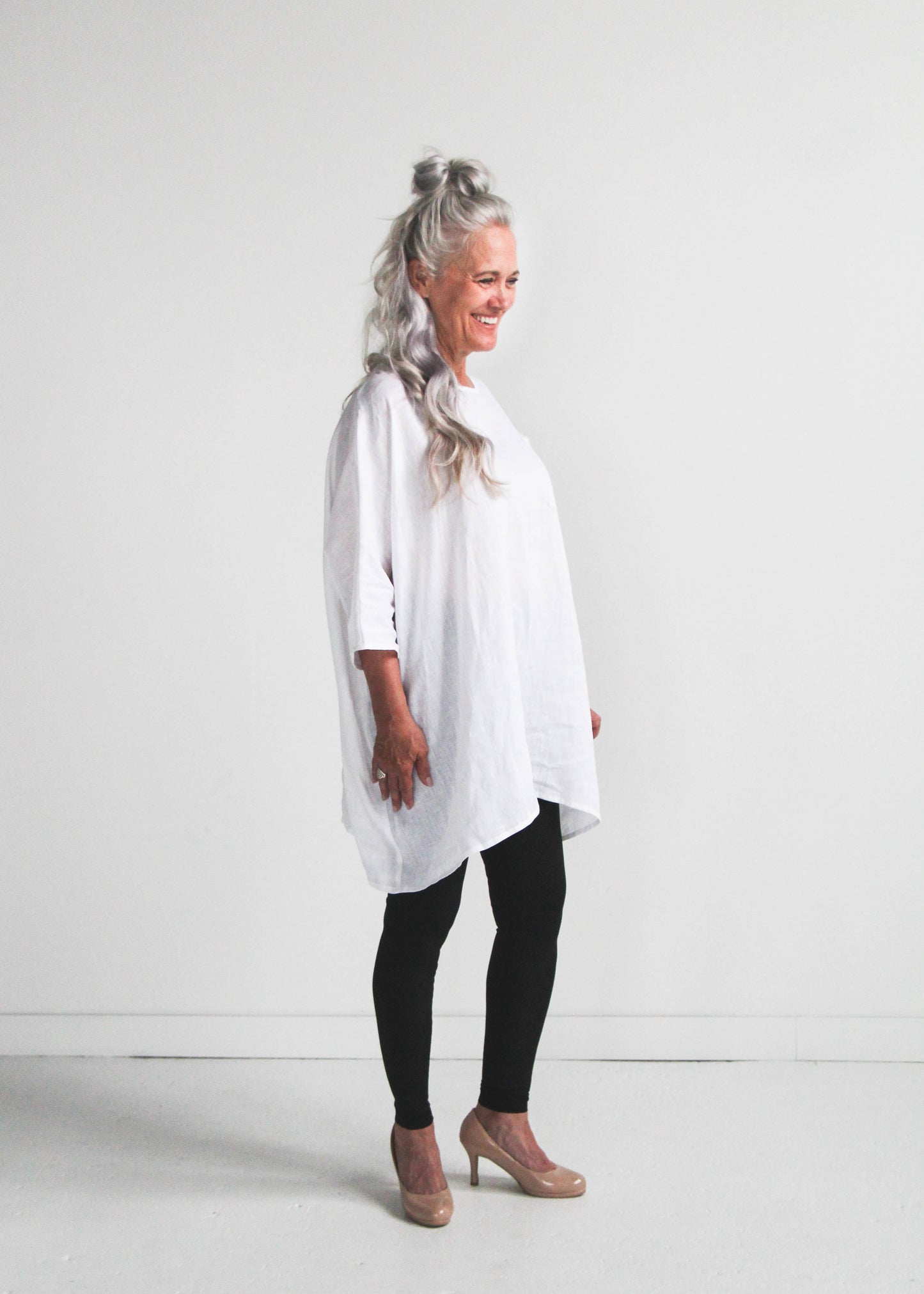 Woman wearing a white shirt and black leggings on a white background