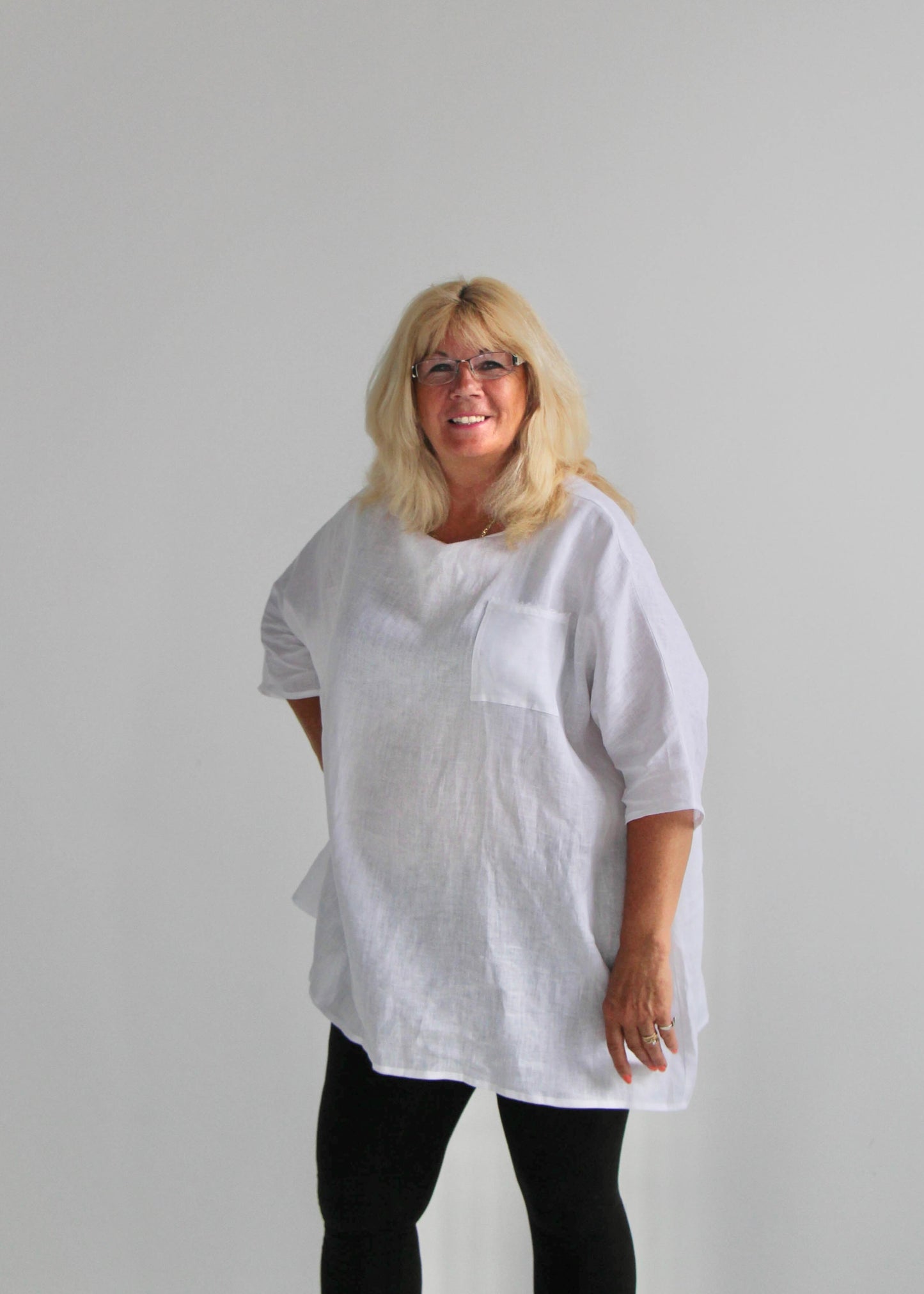 Person wearing a white oversized shirt and black pants against a plain background